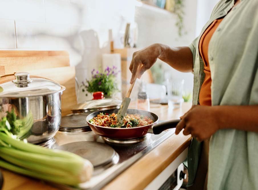 Woman cooking a colourful and nutritious quinoa stir-fry with mixed vegetables and a drizzle of olive oil. This image is for the home page and blog titled CBD Wellness Routine: How to Incorporate Hemp Products into your wellness routine