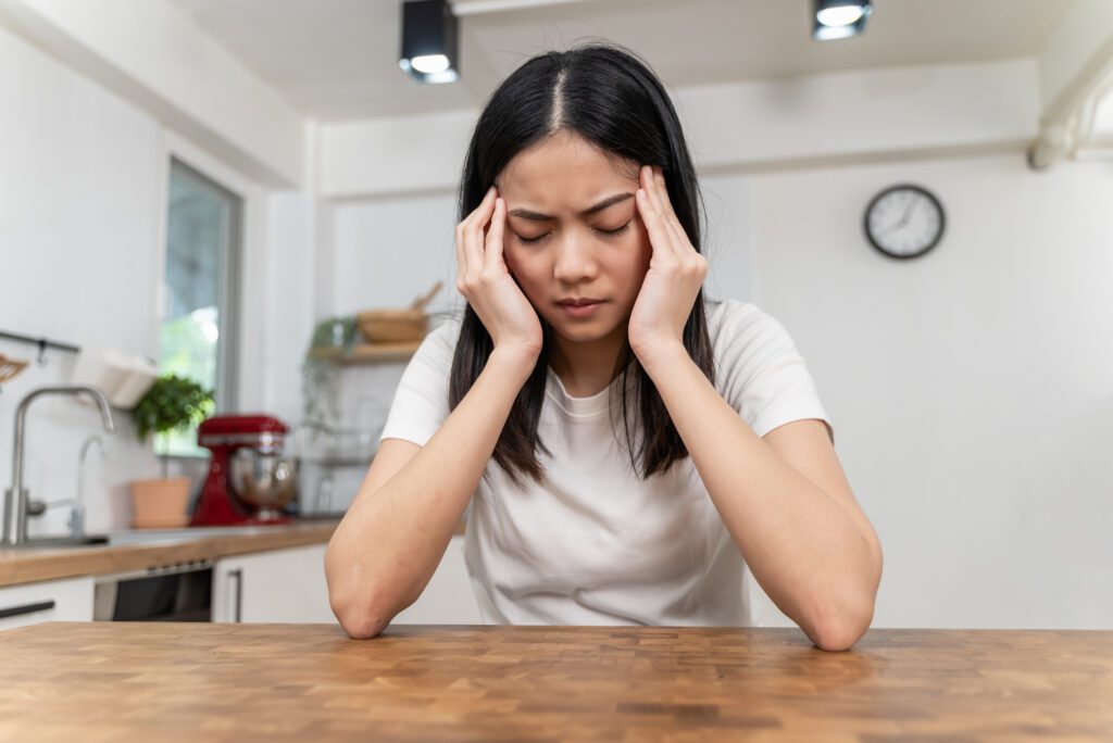 Woman suffering from a migraine sitting alone and rubbing her temples